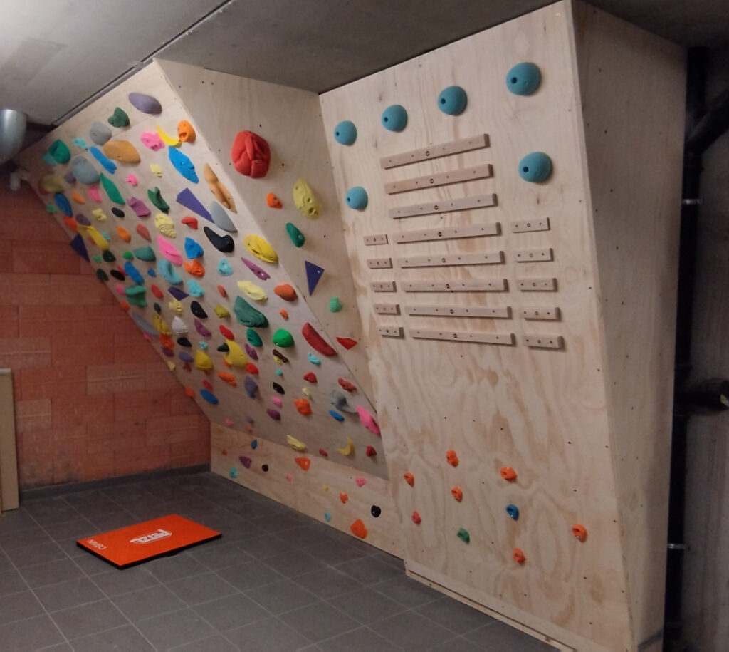 De afgewerkte trainingswand met overhangend klimvlak en campusboard in de kelderruimte