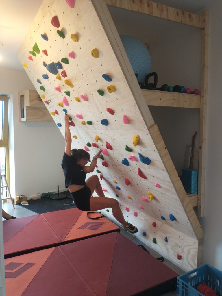 Klimster traint op de steil overhangende wand in de trainingsruimte van klimcoach Francis